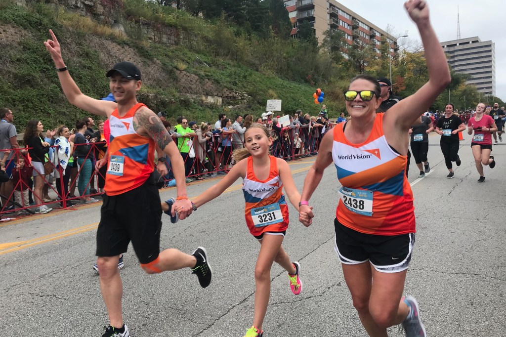 young girl running a race with her parents