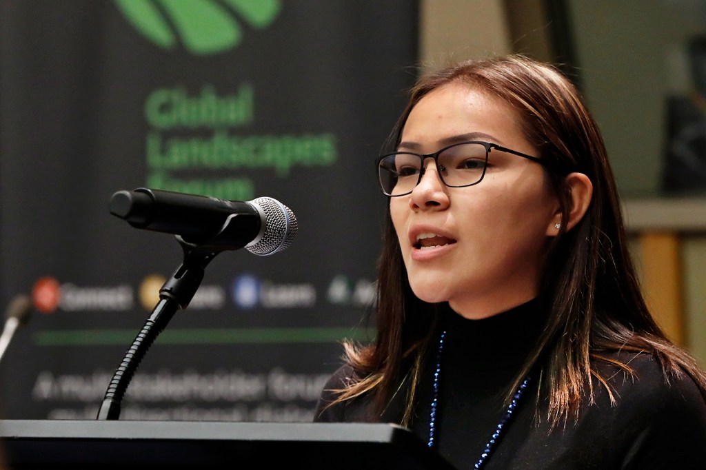 girl with glasses speaking into a microphone on a podium