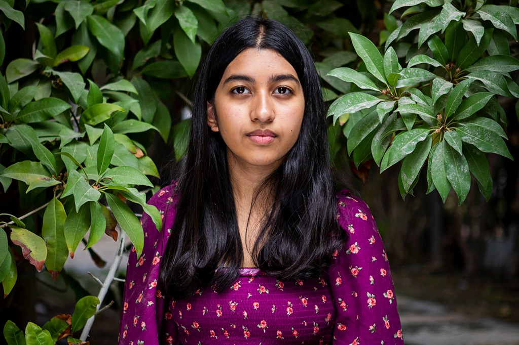 16-year-old in flowered shirt against a leafy background