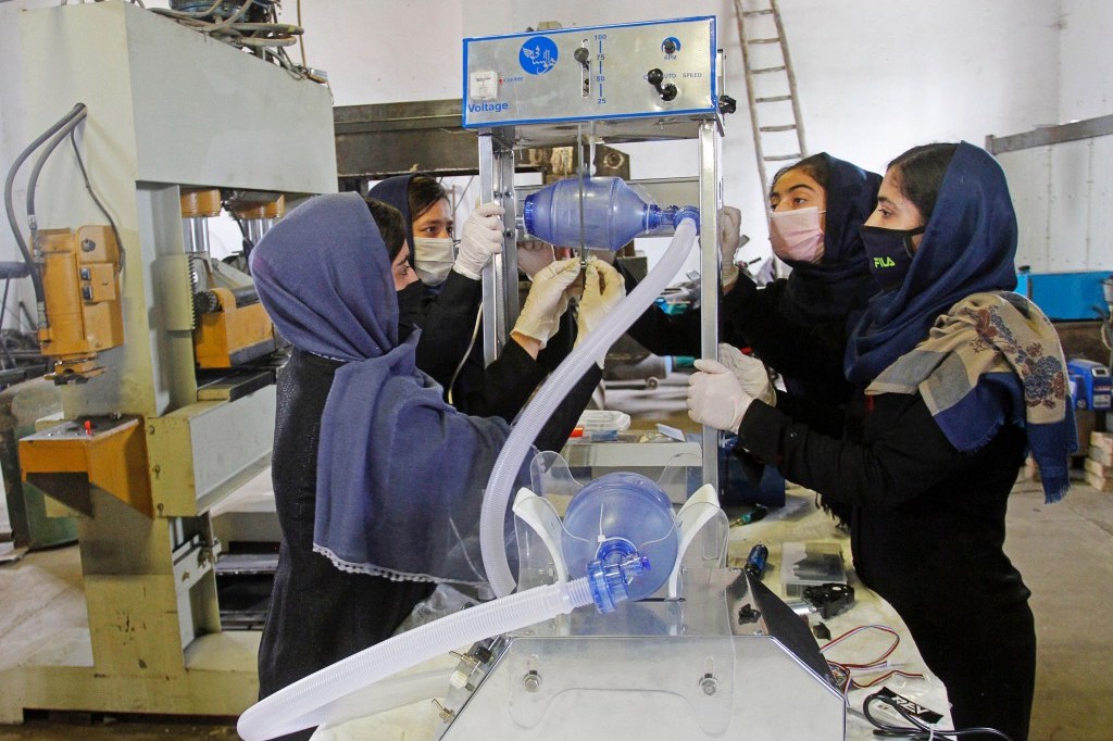 four teens wearing masks working together to build a device