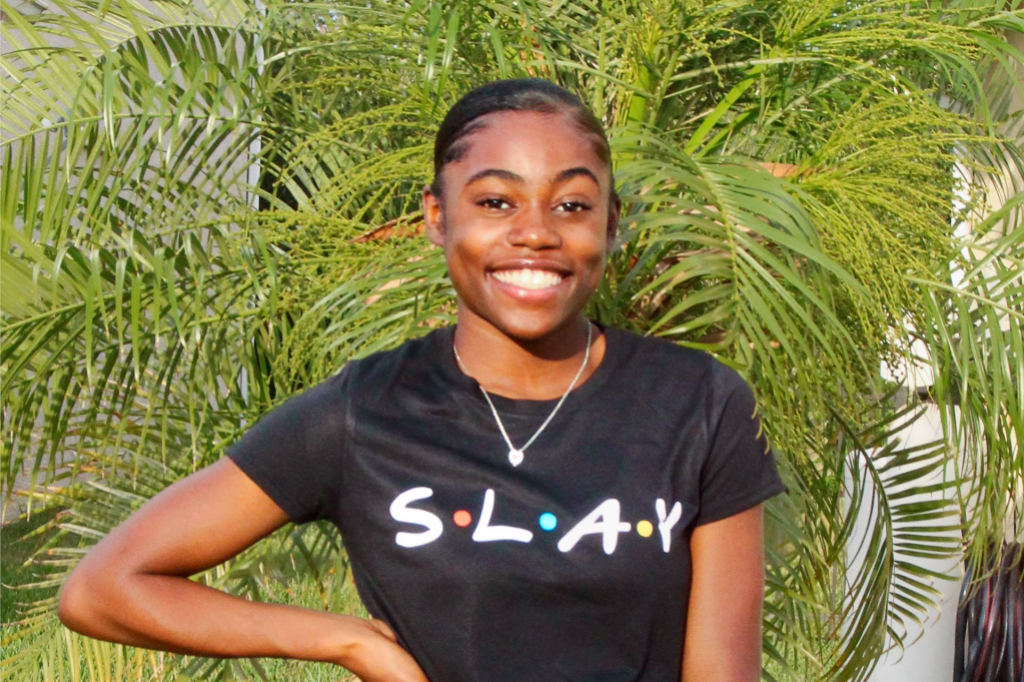 girl in black shirt smiling in front of leaves