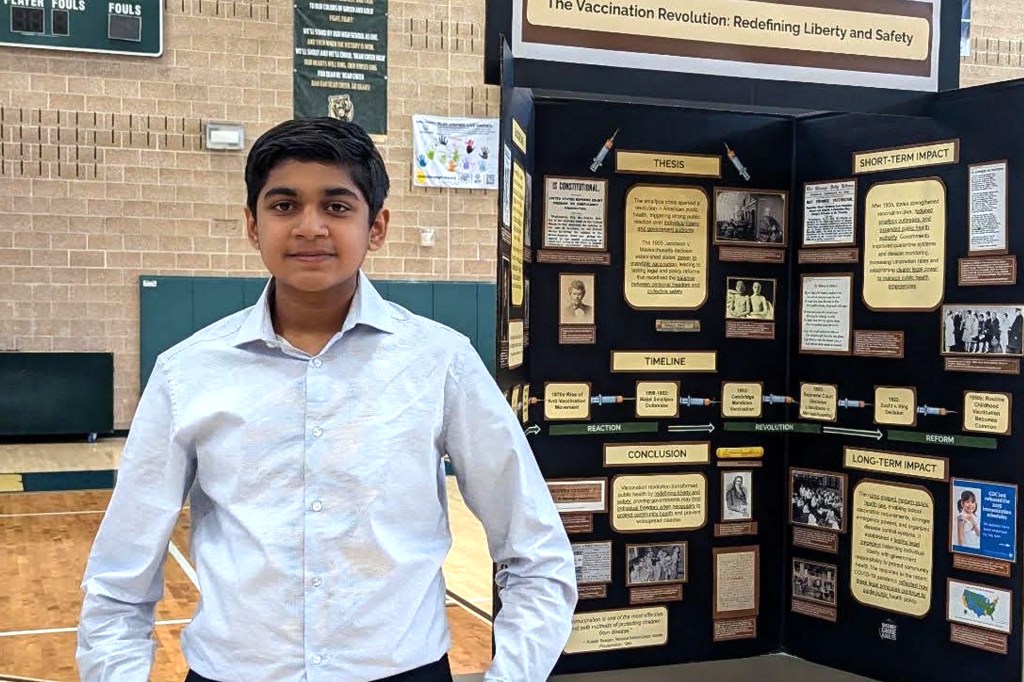 A boy stands beside a school project display.