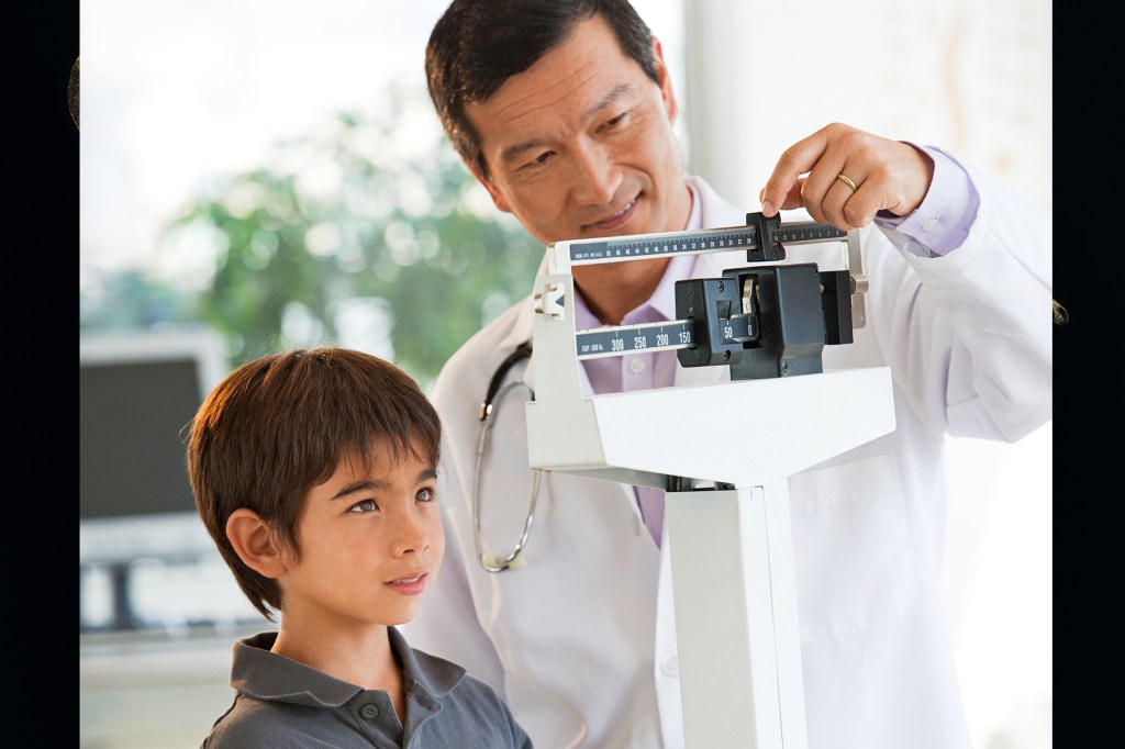 Doctor weighing boy on scale