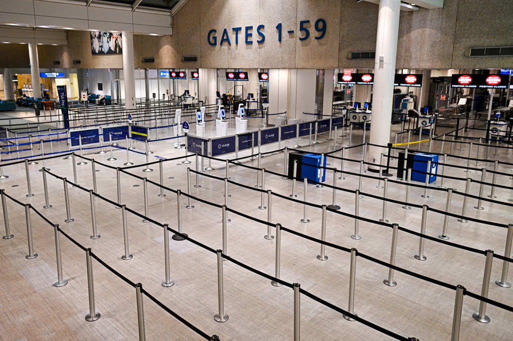 Empty airport security lines with signs showing gates numbered 1 to 59.