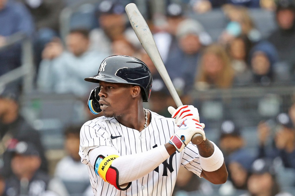 Baseball player in a Yankees uniform stands ready to bat, gripping the bat tightly while focusing on the pitch.