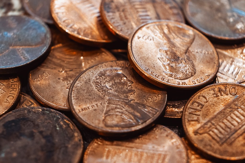 Close-up of a pile of shiny copper pennies, showing the heads and tails of U.S. one-cent coins.