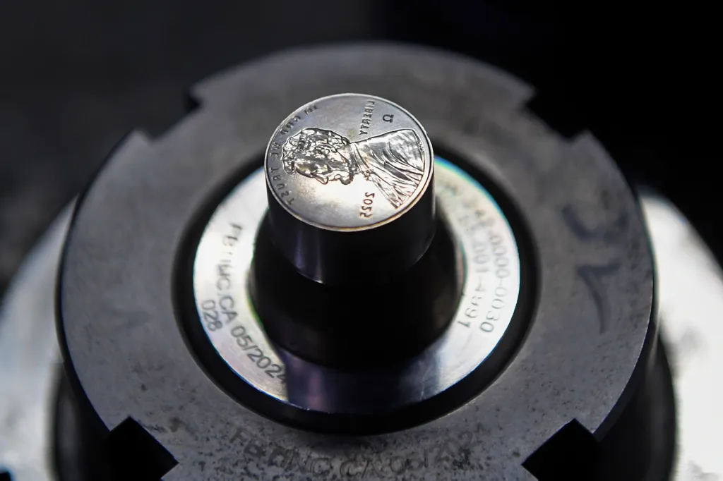 Metal stamp for pennies mounted in a coin‑making machine.