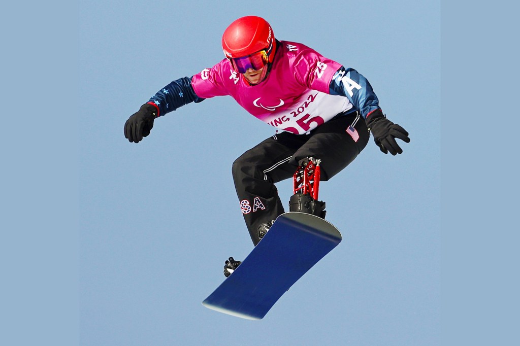 Snowboarder with a prosthetic leg soars high during a jump.