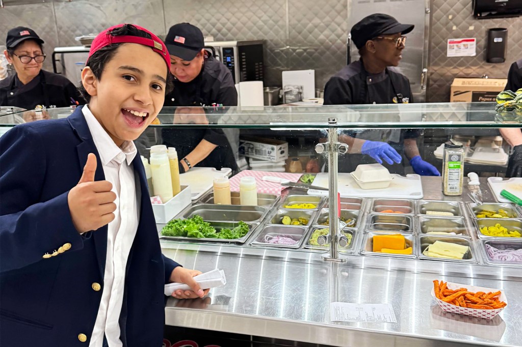 Kid in blazer gives a thumbs‑up at a lunch counter.