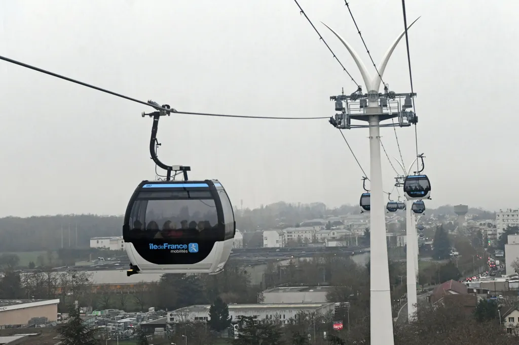 Cable cars glide over a city on overhead wires.