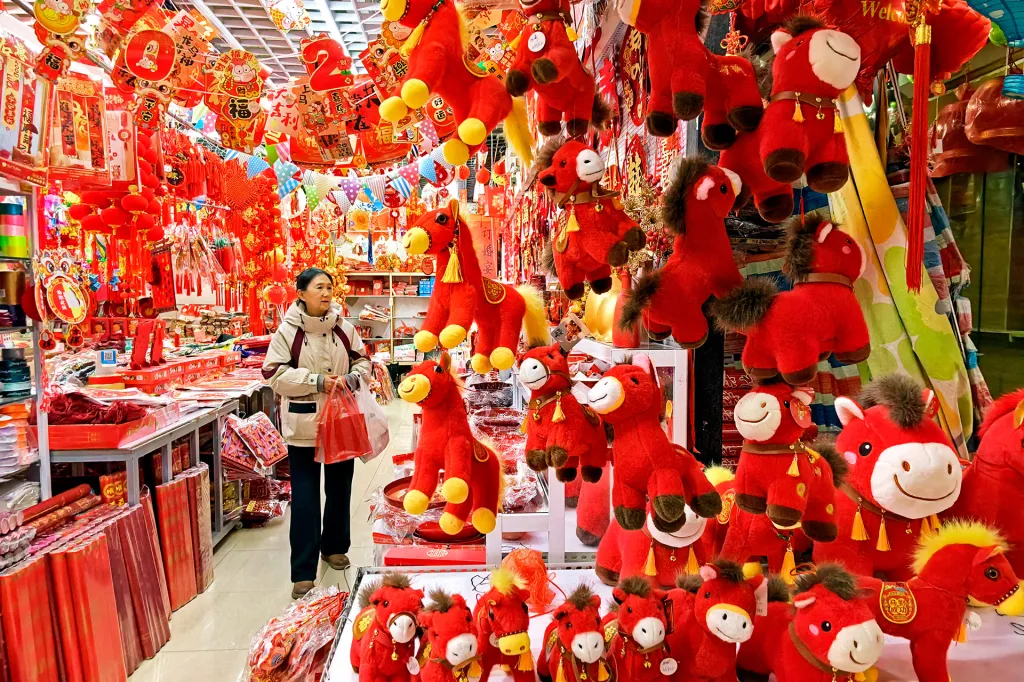 Store full of bright red decorations and plush horses; shopper browses.