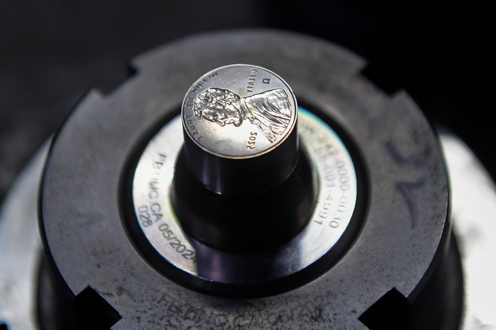 Metal stamp for pennies mounted in a coin‑making machine.