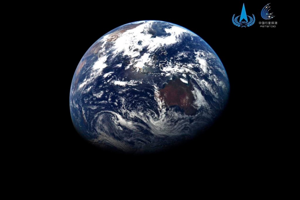 Earth is seen from space against a black background, with blue oceans, white clouds, and parts of Australia and Asia visible.
