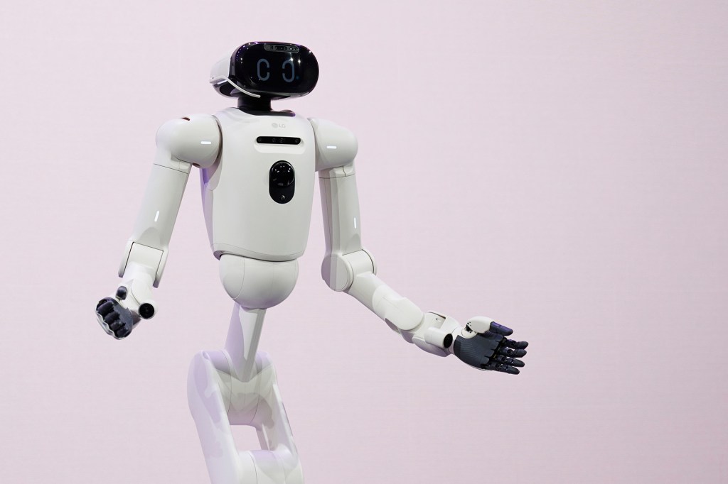 A white robot stands on a stage with its arms open.