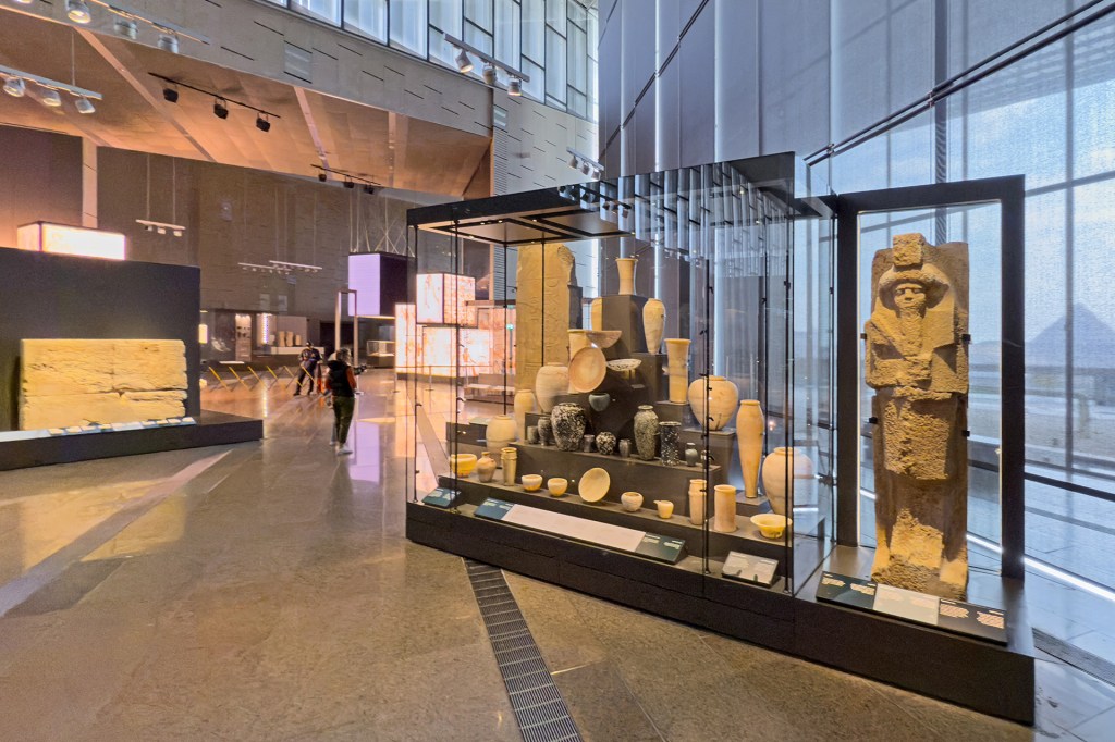 Ancient pots and statues are displayed in glass cases inside a museum.
