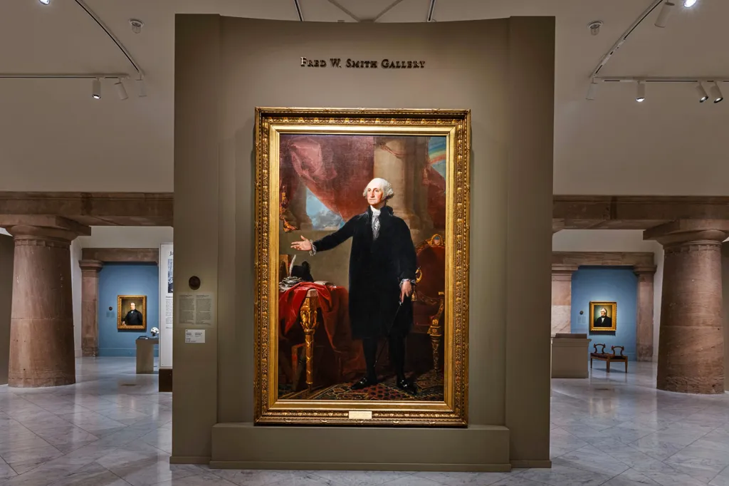 A large framed portrait of George Washington hangs on display inside a museum gallery.