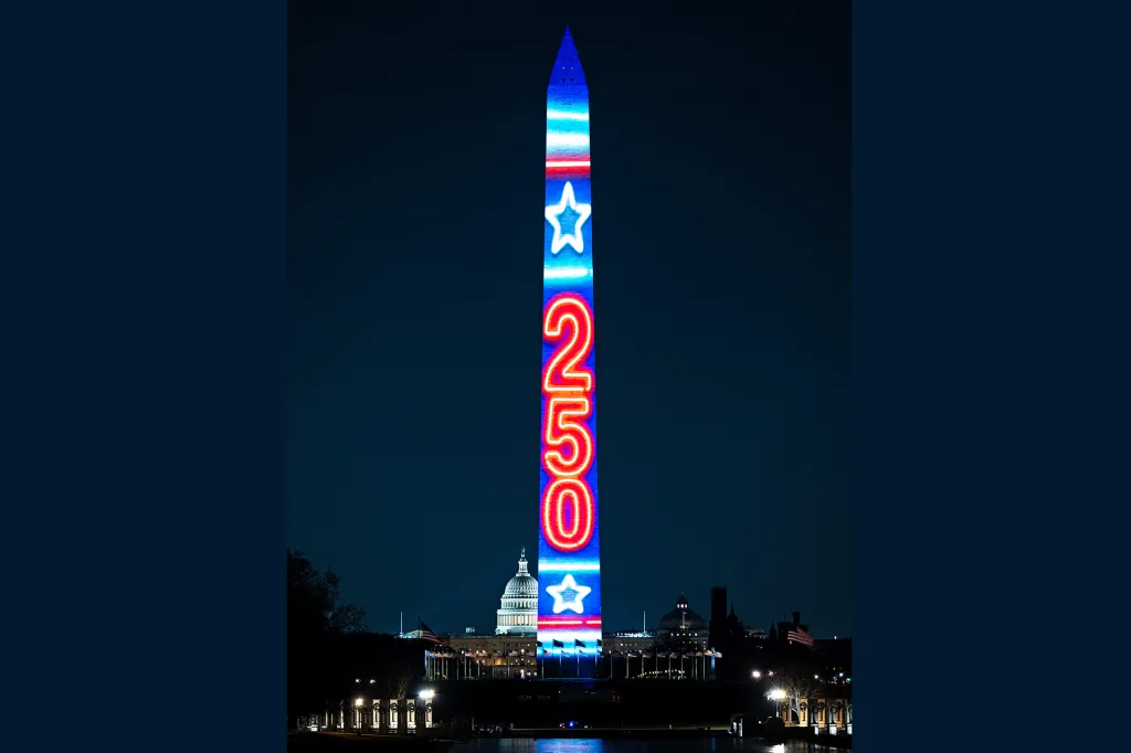 The Washington Monument glows at night with the number “250” lit up in bright red and blue lights.