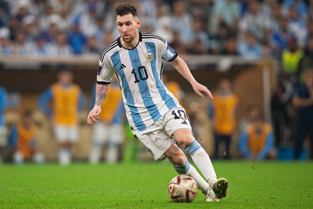 A soccer player in a striped jersey kicks a ball during a game on the field.