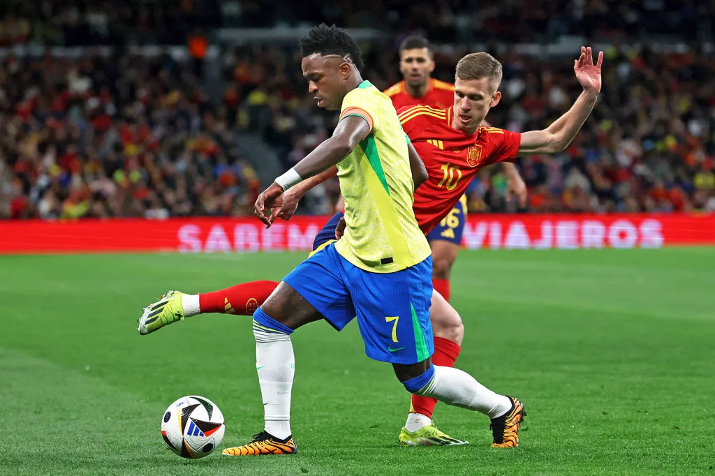A soccer player in a yellow jersey controls the ball as a another player reaches in.