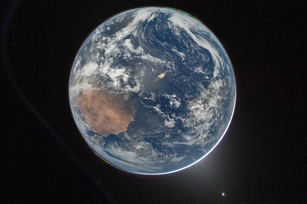 Full view of Earth floating in space, with swirling white clouds, land, and blue oceans.
