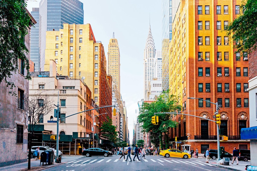 The Empire State Building rises above busy New York City streets at sunset.