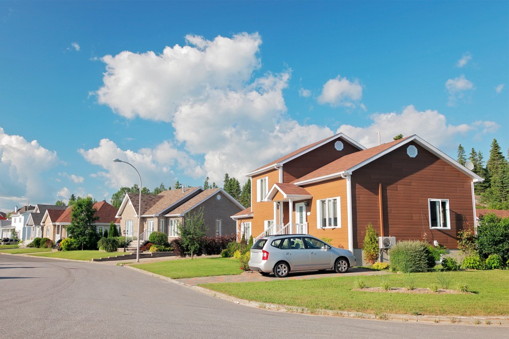 Houses with yards line a quiet neighborhood street.
