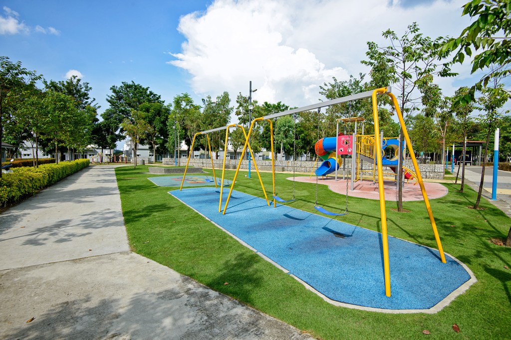 Swings, slides, and play equipment sit in a neighborhood park surrounded by trees.