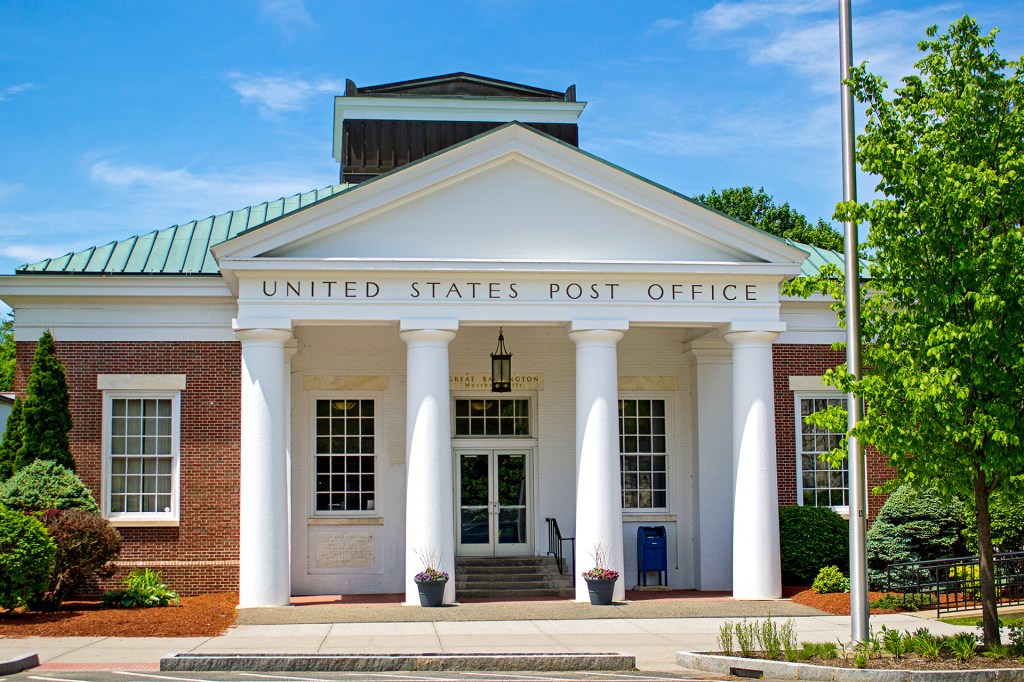 A brick building with white columns and a blue mailbox outside.