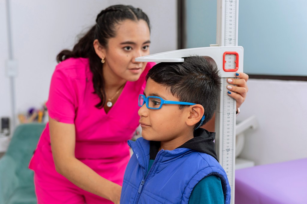 A health worker measures a child's height.