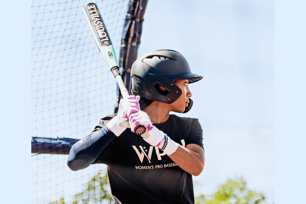 A baseball player wearing a helmet holds a bat and gets ready to hit.