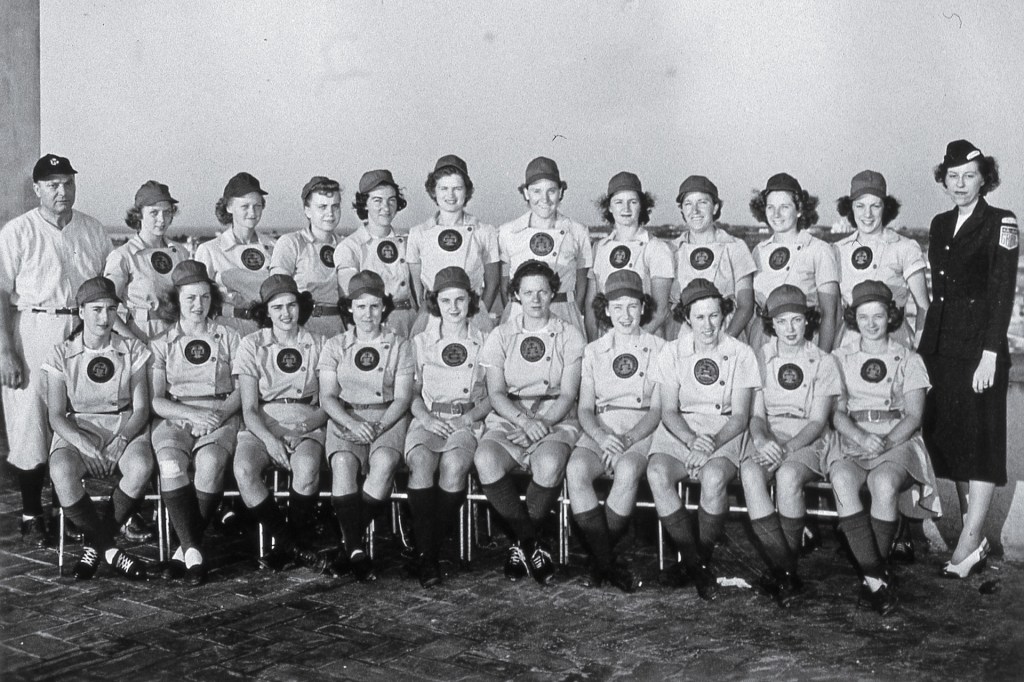 In an old black-and-white photo, a women’s baseball team poses for a group picture.