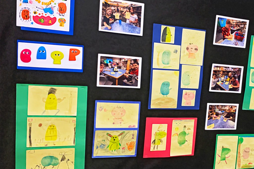 A bulletin board displays children’s colorful drawings and photos of kids making art.