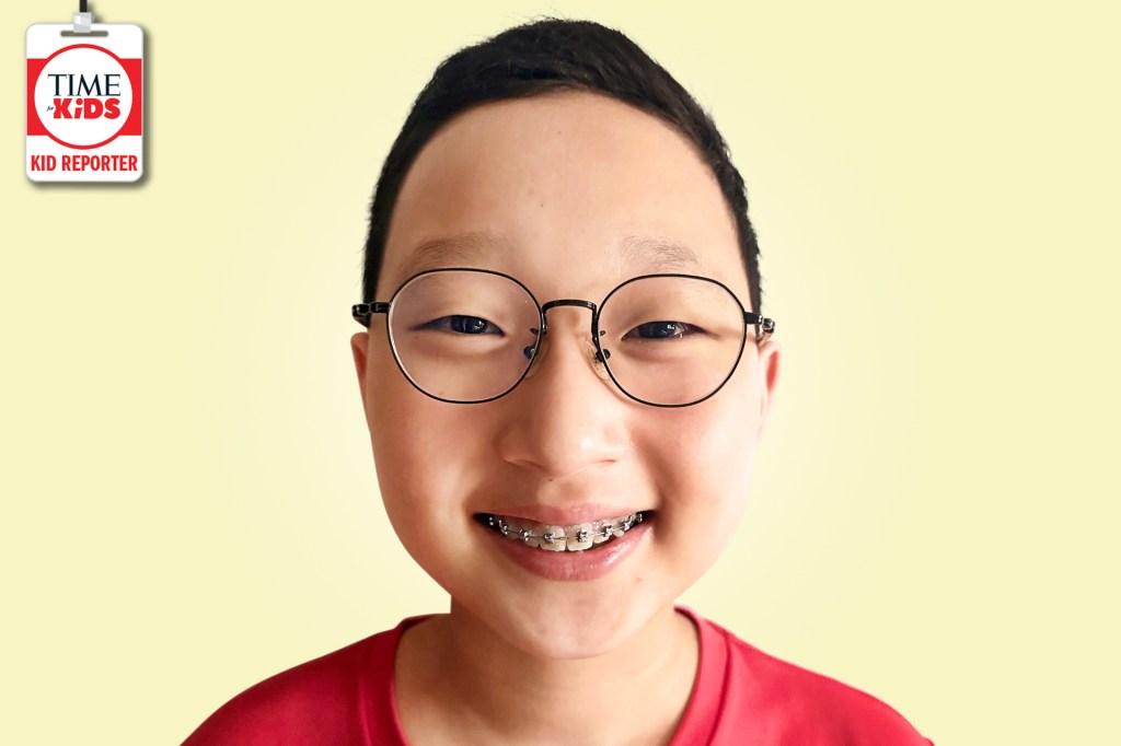 A smiling boy with round glasses and braces poses against a pale yellow background with a TIME for Kids Kid Reporter badge.