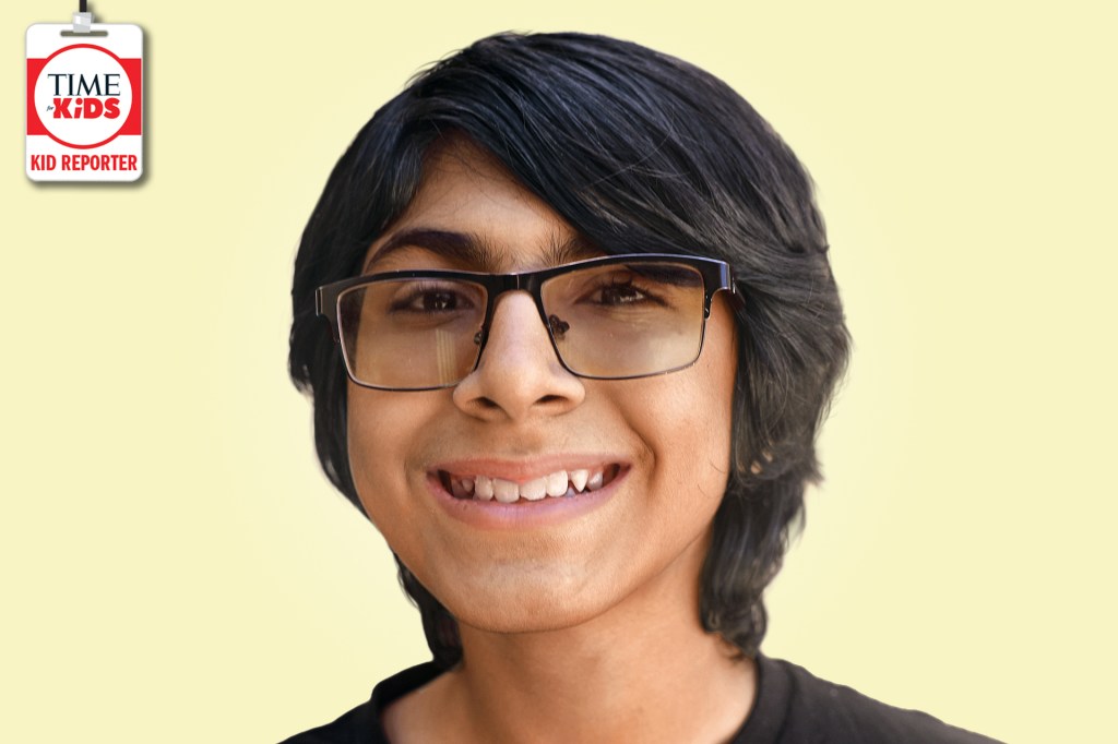 A smiling boy with dark hair and glasses poses against a pale yellow background with a TIME for Kids Kid Reporter badge.