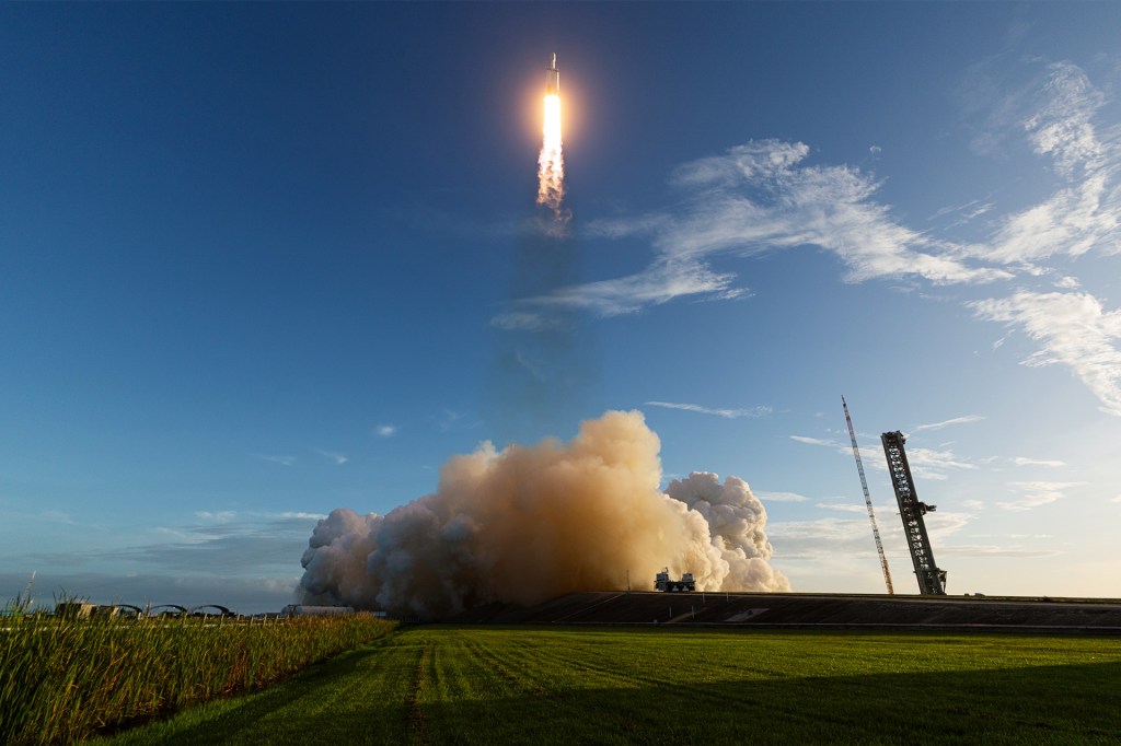 A rocket lifts into the sky above a cloud of smoke.