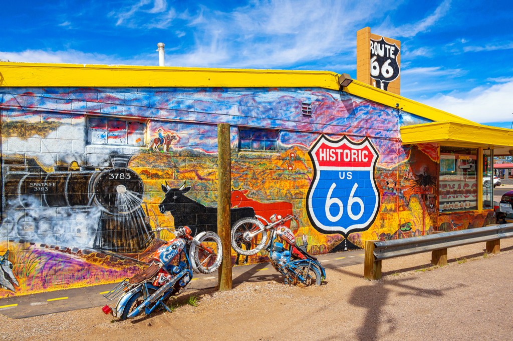 A colorful mural celebrating a historic highway on a roadside building.