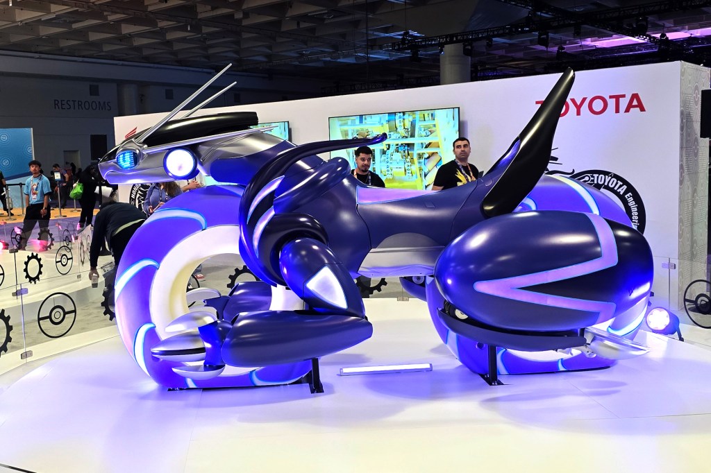 1. A futuristic purple motorcycle-like vehicle with glowing blue accents is displayed at a gaming event.