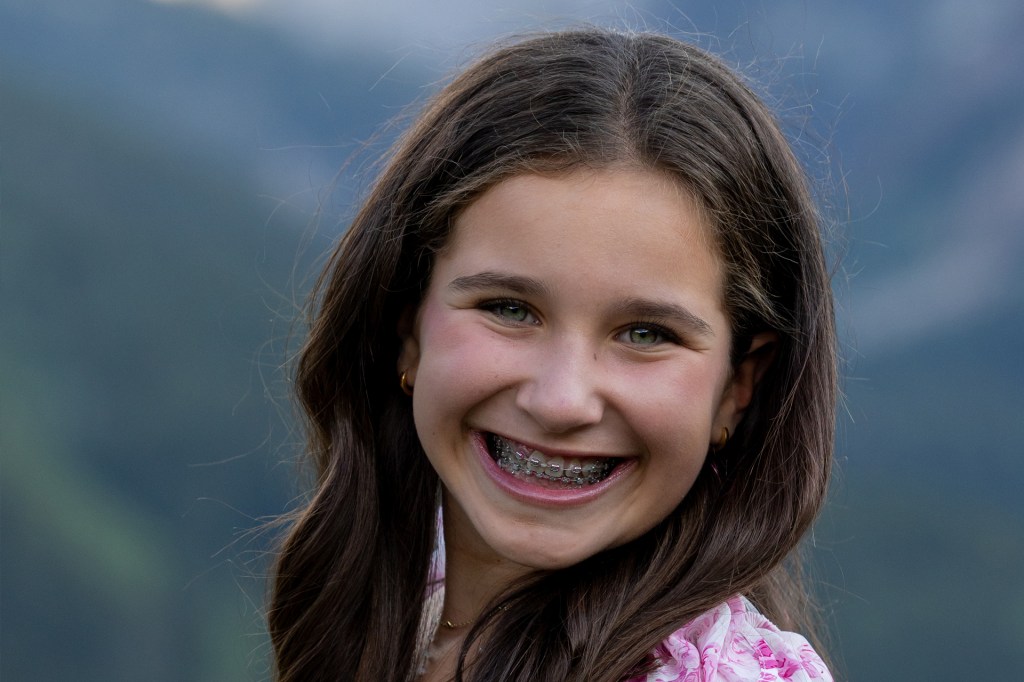 A smiling girl with long brown hair and braces