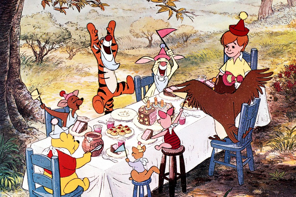 A child sits at a table with animal friends celebrating a birthday with cake and treats.