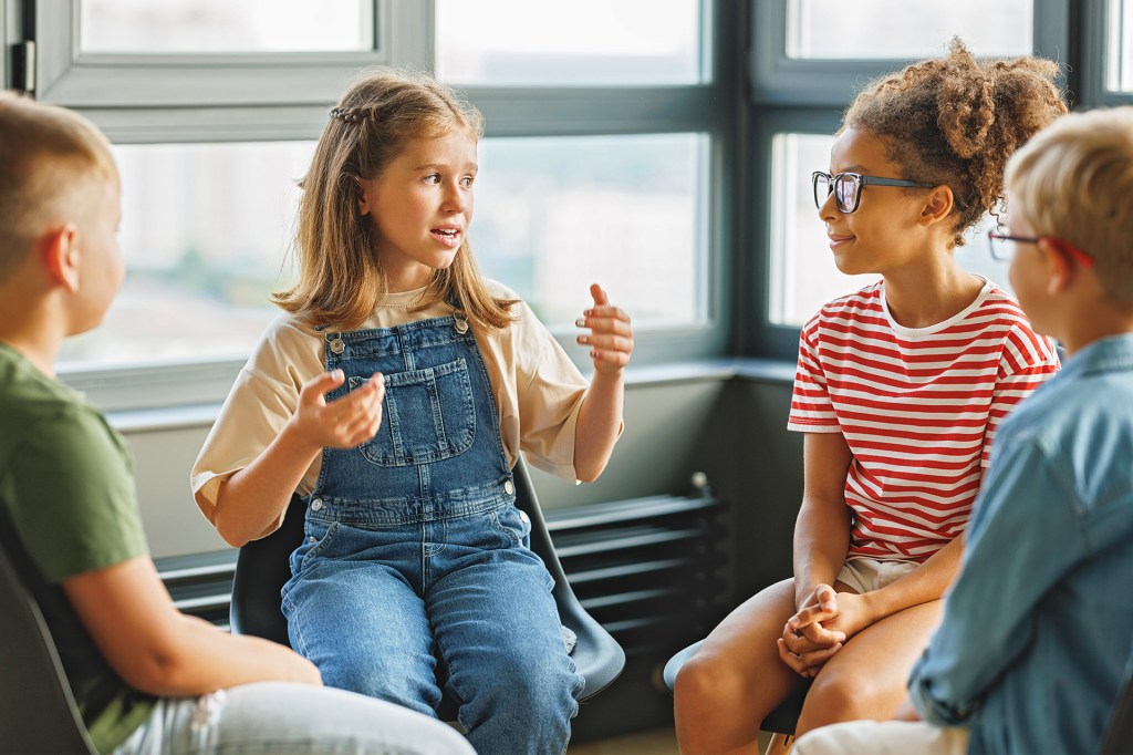 Four children sit in a circle and talk together.